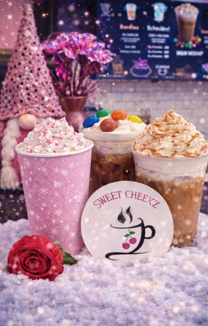 Three seasonal specialty coffee drinks with whipped cream displayed inside Sweet Cheekz Cafe N’ Bistro